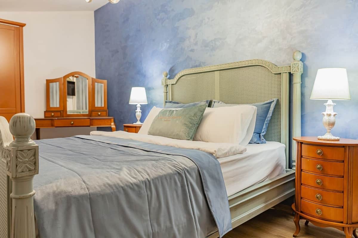 A bedroom with a bed, two bedside tables with lamps, a dresser, and a mirror.