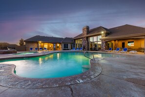 A swimming pool with lounge chairs, a stone facade, and a sunset sky. - Almost Heaven 4 Bedroom Apts by RedAwning (Washington)