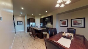 A spacious kitchen with dark wood cabinets, a central island, and a dining area with a wooden table and chairs.