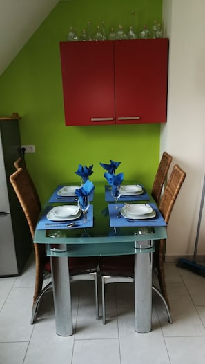 Un tavolo da pranzo con tovagliette blu, piatti bianchi e fiori di tovagliolo blu, con una parete verde e un armadietto rosso sopra.