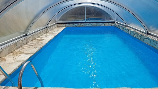 Une piscine bordée de pierres et dotée d’un escalier en métal.