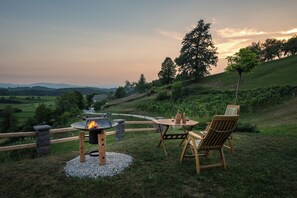 Ein Außenbereich mit Sitzgelegenheit, einem Feuerkorb, Holzstühlen und einem Tisch.