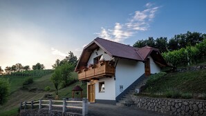 Een huis met twee verdiepingen, een houten balkon, stenen trappen en een stenen muur.