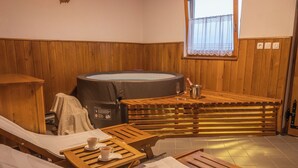 Een kamer met een houten bank, een jacuzzi en een raam met uitzicht.