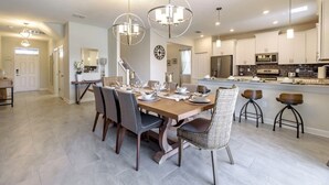 Un vaste espace dédié à la salle à manger, avec une table en bois dressée pour six personnes, entourée de chaises.