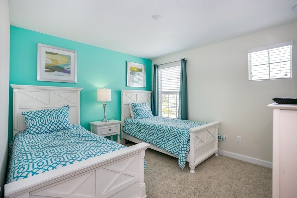 A bedroom with two beds, a nightstand, a dresser, and a window with curtains.