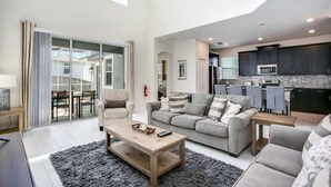 A spacious living room with a grey sofa, a wooden coffee table, and a large window. - 1585tempo 5 Bedroom Home by RedAwning (Davenport)