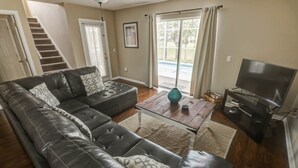 A living room with a sectional sofa, a coffee table, a TV, and a staircase.