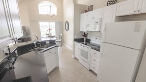 A modern kitchen with white cabinets, a black countertop, and a built-in oven. - Serene Private Pool In Southern Dunes! 4 Bedroom Home by RedAwning (Haines City)