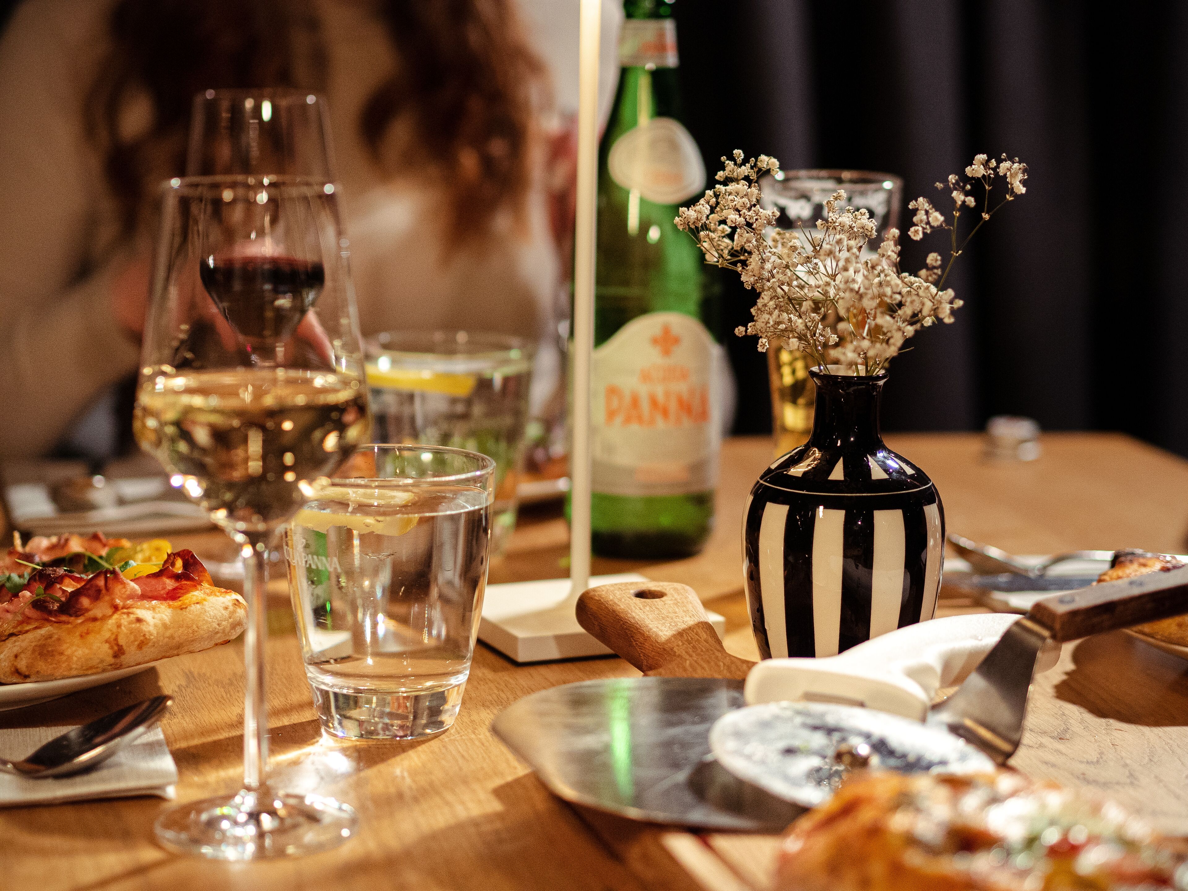 A dining table with various food items, glasses of water and wine, and a bottle of wine.