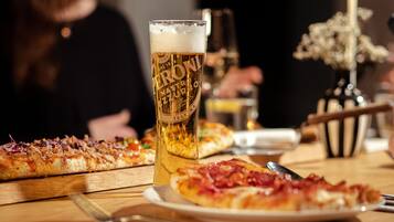 A table with a glass of beer, a pizza, and a fork.