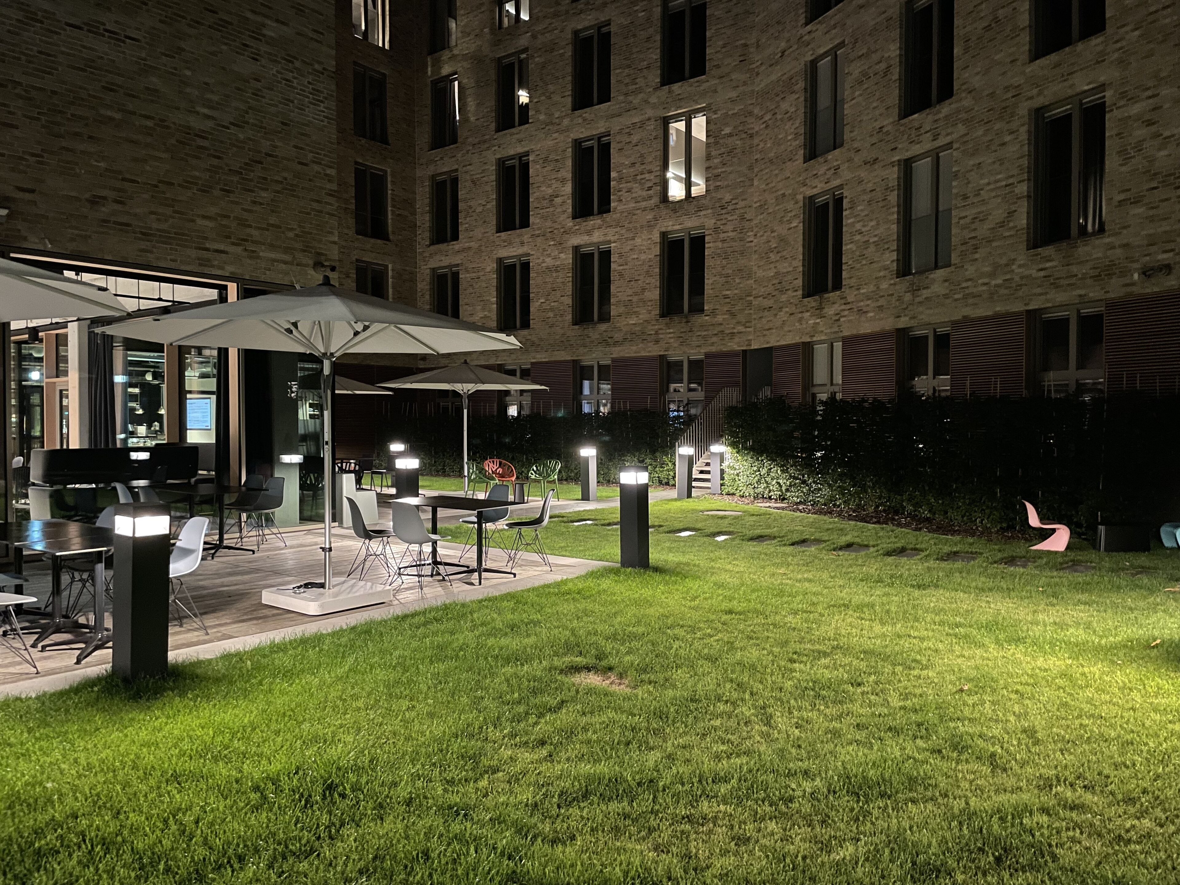 A courtyard with outdoor seating, a piano, and a brick building in the background.