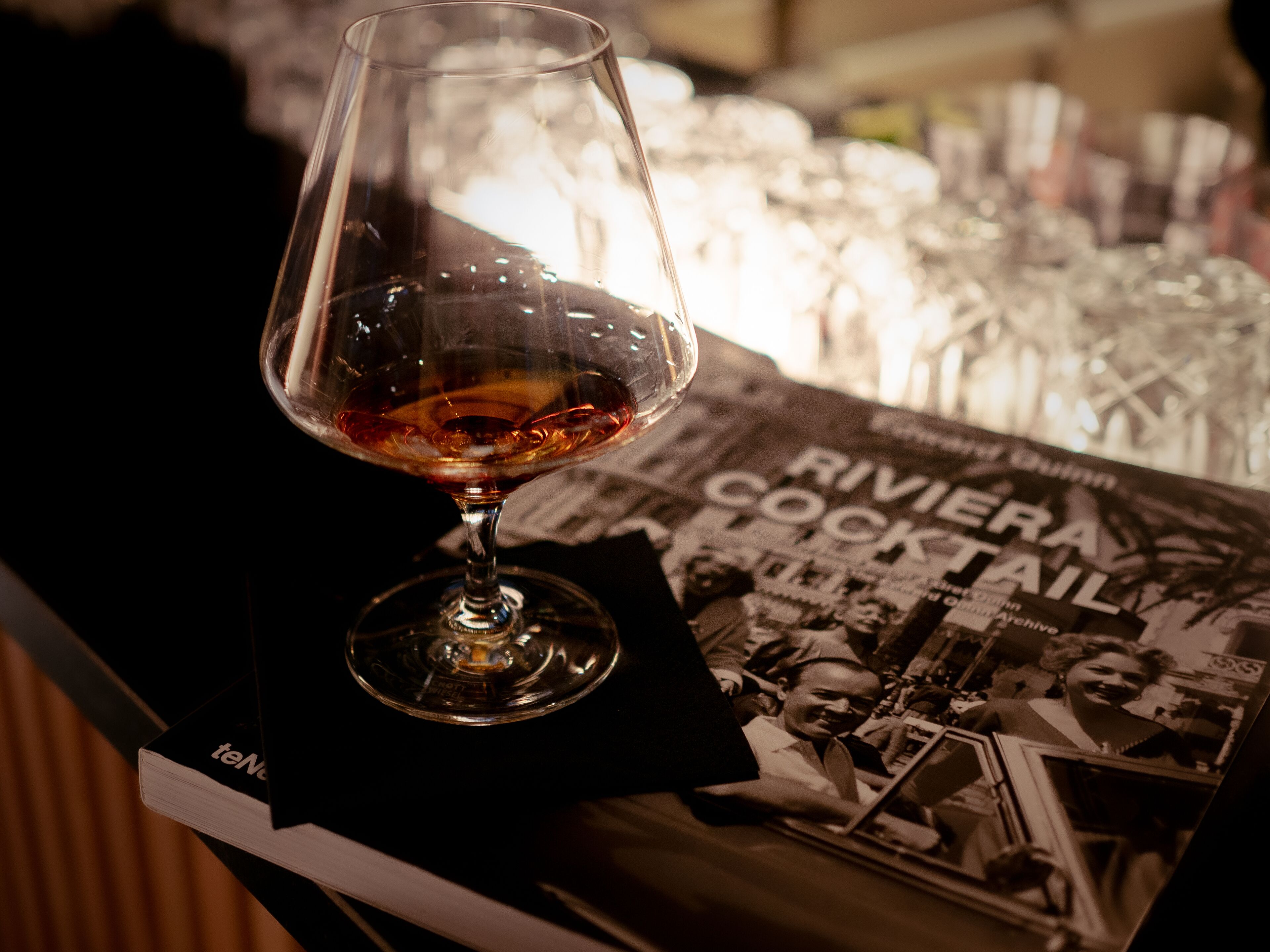 Ein Glas Rotwein auf einem Tisch mit einer Zeitschrift, die ein Cocktailrezept zeigt.