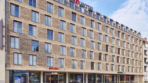 Ein Hotel mit moderner Ziegel Fassade, mehreren Balkonen und blauem Himmel.
