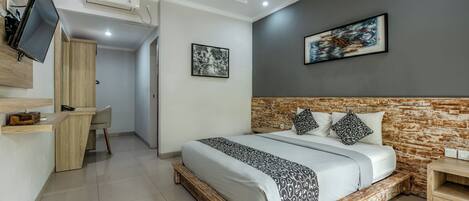 A modern bedroom with a large bed, a desk, and a TV.