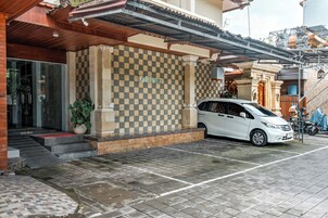 A building entrance with a checkered wall, a white car parked in front, and a staircase leading up.