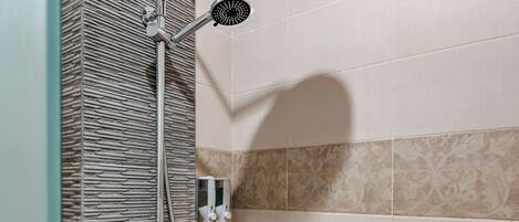 A shower with a rain showerhead, handheld showerhead, and a handheld faucet.