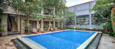 A swimming pool with lounge chairs and a staircase leading to an upper level.