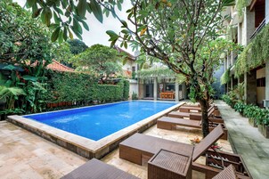 Piscina com espreguiçadeiras e vegetação.