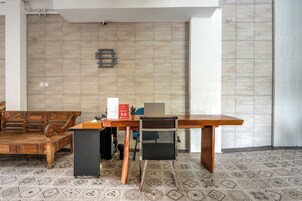 Um espaço de escritório moderno com escrivaninha de madeira, cadeira preta e banco de madeira.