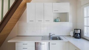 A modern kitchen with white cabinets, a stainless steel sink, and a coffee maker. - Berghütte Innsbruck (Innsbruck)