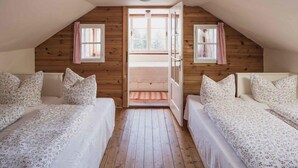 A bedroom with two beds, wooden walls, and a large window. - Berghütte Innsbruck (Innsbruck)