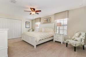 A bedroom with a bed, bedside tables, a chair, a ceiling fan, and a window with blinds. - Best Resort In Disney Area! 6 Bedroom Villa by RedAwning (Davenport)