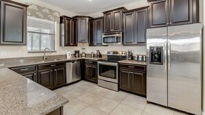 A modern kitchen with dark cabinetry, stainless steel appliances, and a granite countertop.