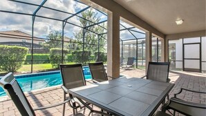 A covered patio with a pool, outdoor seating, and a view of the surrounding landscape.