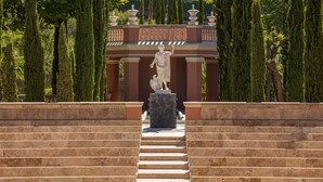 Una escalera de mármol que conduce a una estatua en un jardín formal.