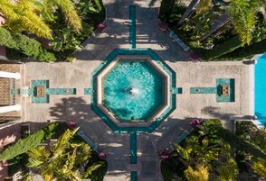 Vista aérea de una piscina rodeada de palmeras y un sendero empavedado.
