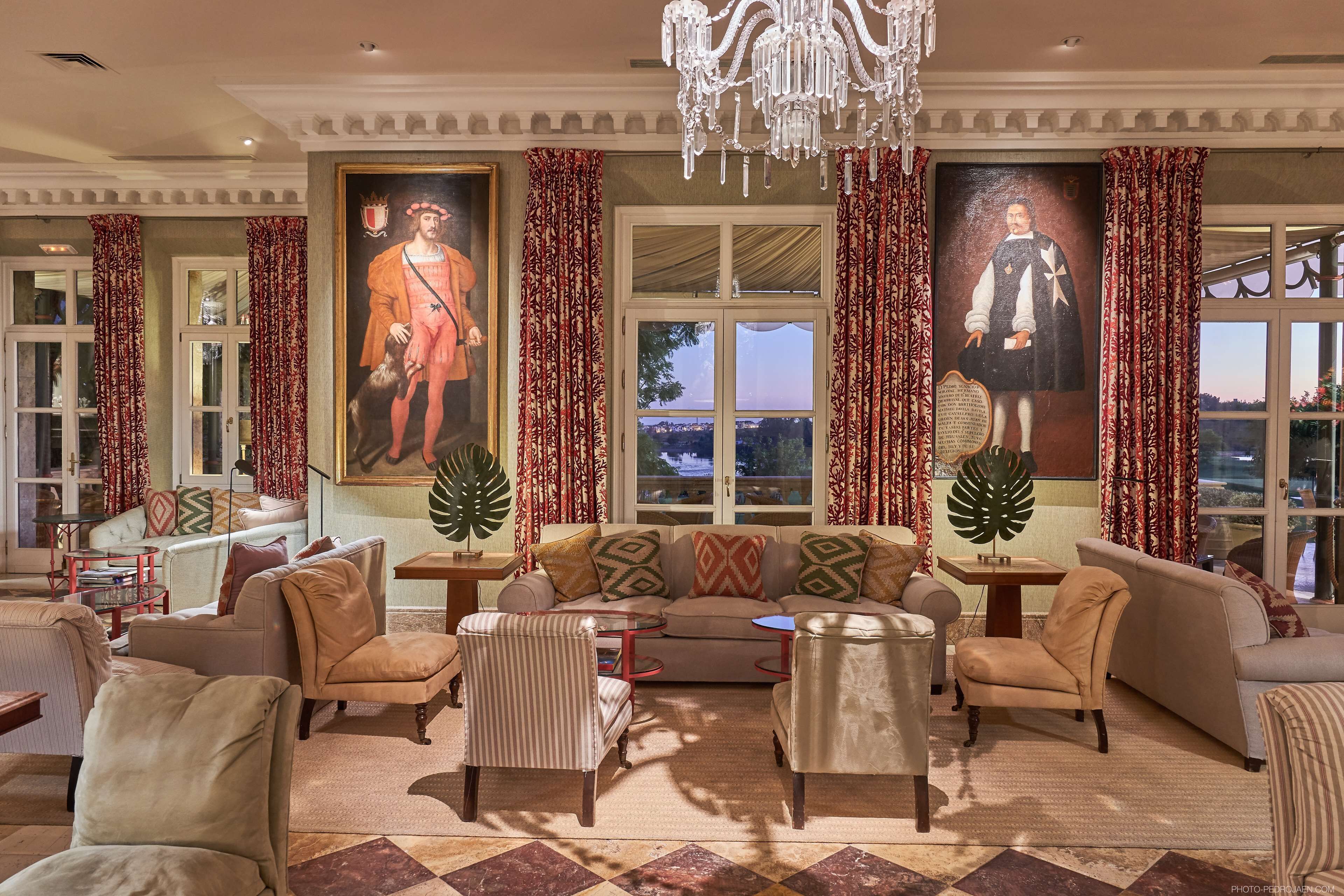 A spacious living room with a large sofa, armchairs, and a chandelier.