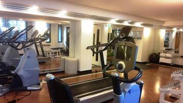 Un gimnasio con máquinas de cardio, un espejo y una cinta de correr.