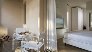 A hotel room with a bed, a desk with a computer, a chair, and a table with breakfast items. - Embassy Aparthotel (Rimini)