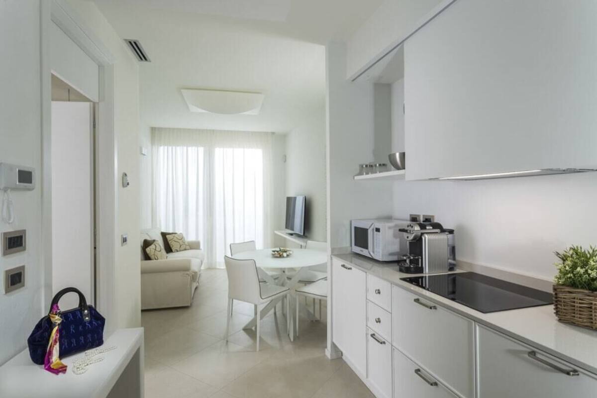 Una cocina moderna con armarios blancos, un microondas integrado y una placa de inducción negra.