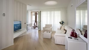 A modern living room with a flat-screen TV, a sofa, a chair, and a coffee table. - Embassy Aparthotel (Rimini)