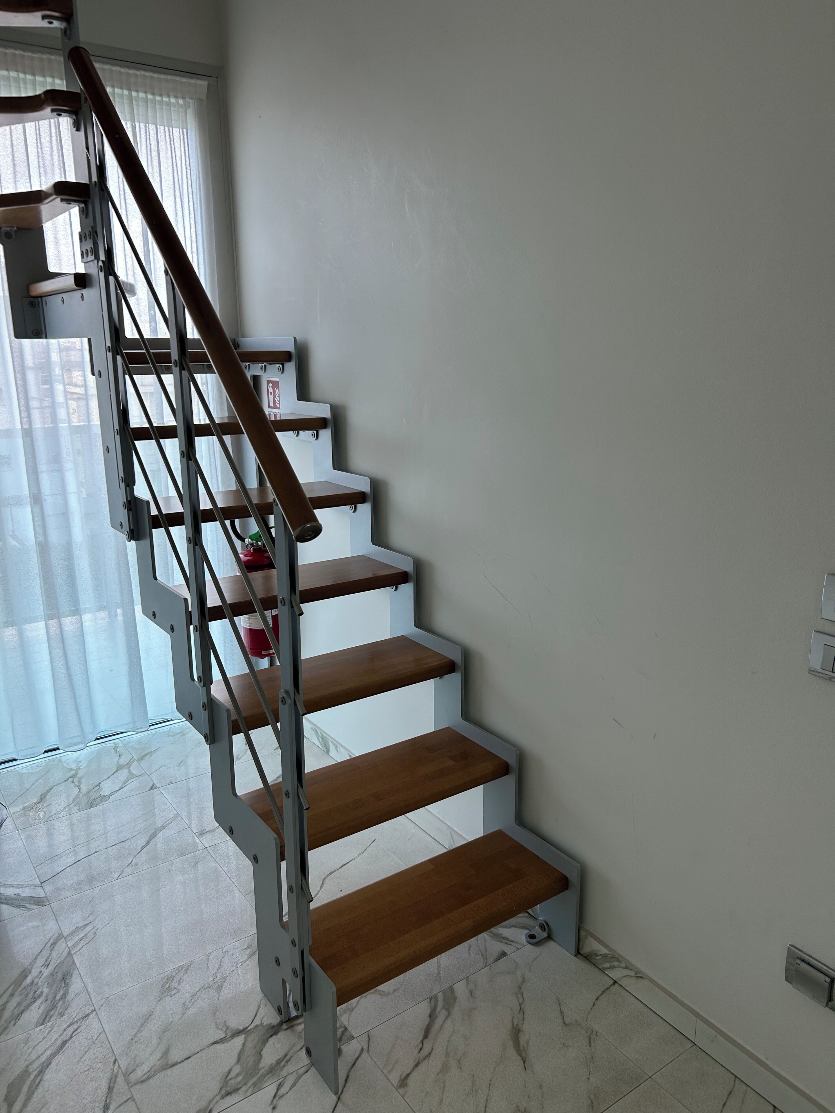 A staircase with wooden steps and metal railings, leading to an upper floor.