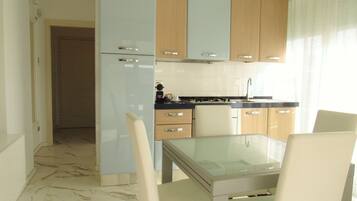 Una cucina moderna con tavolo e sedie in vetro, mobili in legno e pavimento piastrellato.