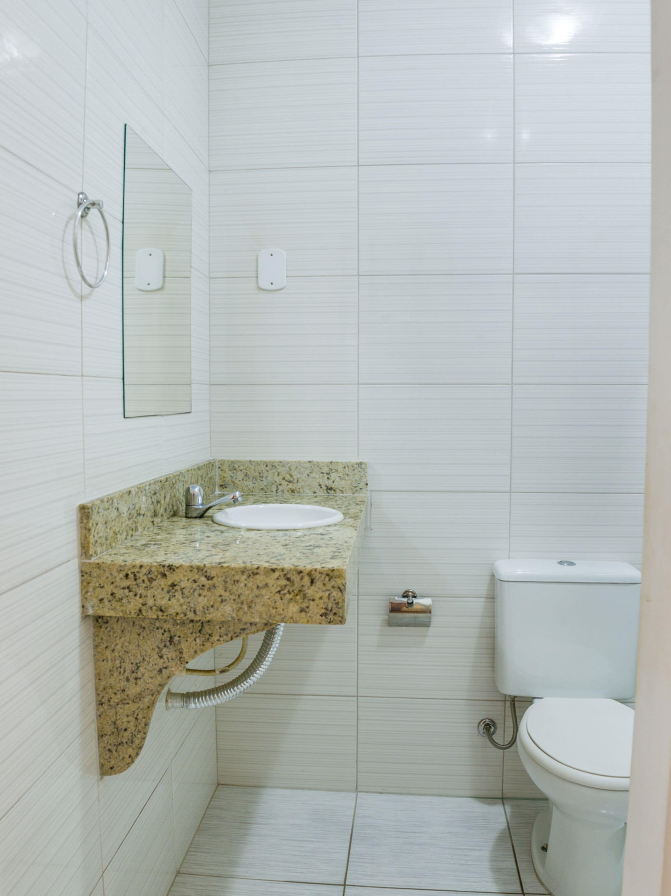 A bathroom with a granite countertop sink, a mirror, a toilet, and a shower.