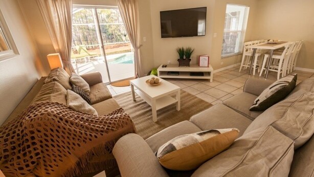 A living room with a sofa, coffee table, TV, and a dining area with chairs and a table.