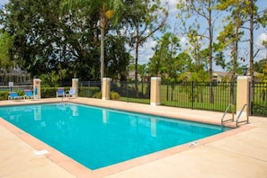 A rectangular swimming pool with a clear blue water surface, surrounded by a paved deck.