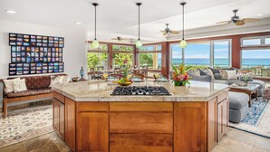 Una cocina amplia con una isla grande, armarios de madera y vista al océano.