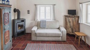 A cozy living room with a sofa, a fireplace, a television, and a window with curtains. - Stoantaler Höfl (Innsbruck)