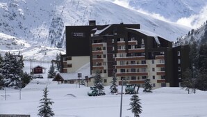 Un hotel de varios pisos con un paisaje de estación de esquí, destacando un cartel con la inscripción 'Les Rendeurs'.