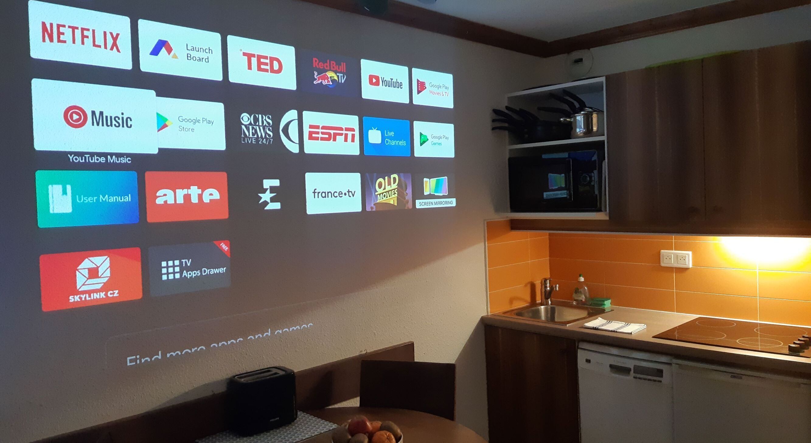 A kitchen with a wall-mounted projector displaying various app icons.