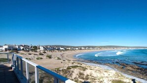 Vista costera con una playa, olas del océano y una hilera de edificios blancos a lo largo de la orilla.