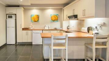 A modern kitchen with white cabinets, a wooden countertop, and two bar stools.