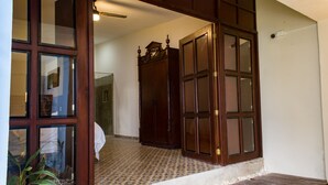 A wooden door with glass panels, a tiled floor, and a small step leading to a hallway. - Hotel Maculís (Campeche)