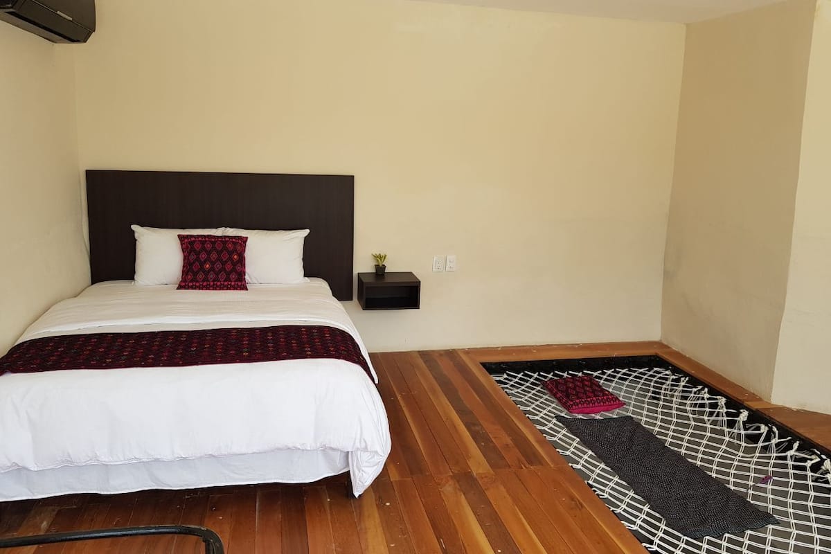 Una camera da letto con un letto, un comodino, un condizionatore d'aria a parete e un pavimento in legno.