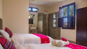 A hotel room with two beds, a bathroom, and a shower area. - Hotel Maculís (Campeche)